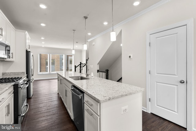 kitchen featuring white cabinetry, sink, hanging light fixtures, stainless steel appliances, and a center island with sink