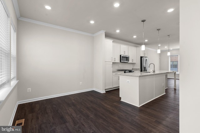 kitchen featuring white cabinetry, decorative light fixtures, an island with sink, and appliances with stainless steel finishes