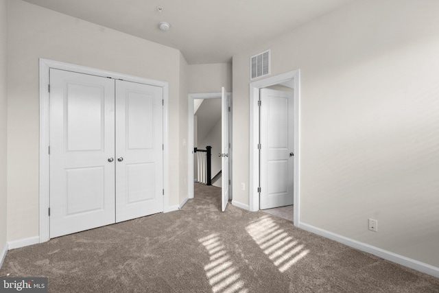 unfurnished bedroom with light colored carpet and a closet