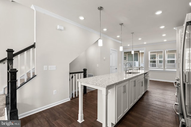 kitchen featuring decorative light fixtures, white cabinetry, an island with sink, sink, and light stone counters