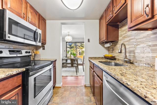 kitchen with light stone counters, sink, tasteful backsplash, and stainless steel appliances