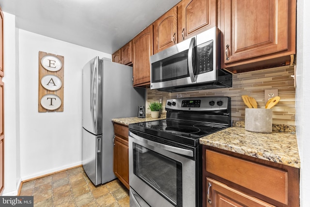 kitchen with appliances with stainless steel finishes, light stone counters, and decorative backsplash