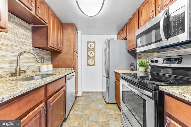 kitchen featuring light stone countertops, appliances with stainless steel finishes, sink, and decorative backsplash