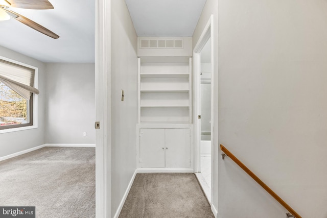 walk in closet with light carpet and ceiling fan