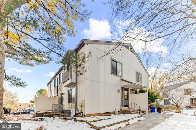 snow covered house featuring central AC unit