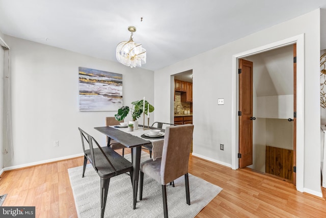 dining area with light hardwood / wood-style floors and a notable chandelier