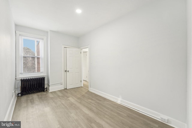 spare room featuring radiator heating unit and light wood-type flooring