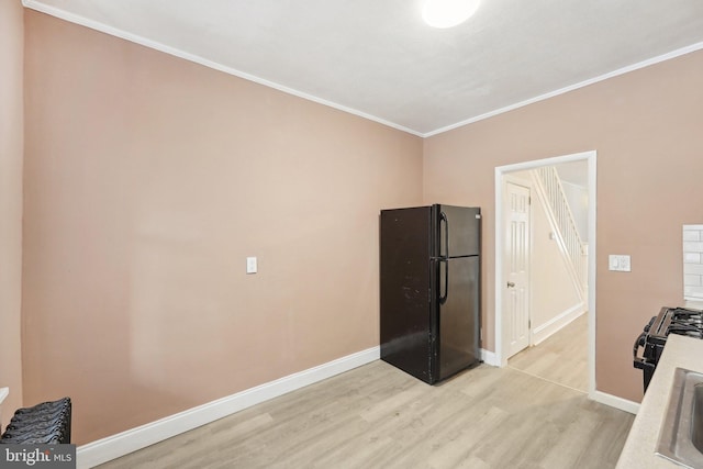 kitchen with black appliances, crown molding, and light wood-type flooring