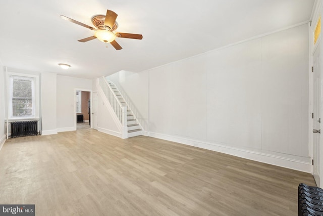 unfurnished living room featuring radiator heating unit, light hardwood / wood-style floors, and ceiling fan