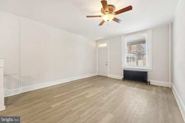 spare room with radiator heating unit, light hardwood / wood-style floors, and ceiling fan