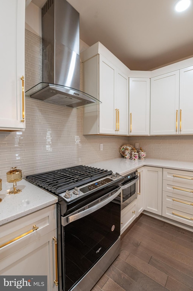 kitchen featuring wall chimney exhaust hood, stainless steel gas range, and white cabinets