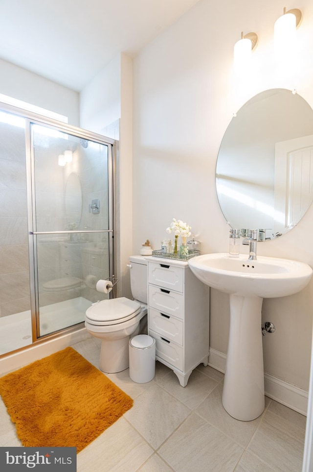 bathroom with tile patterned flooring, toilet, and a shower with shower door