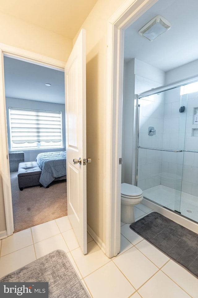 bathroom featuring tile patterned floors, toilet, and a shower with door