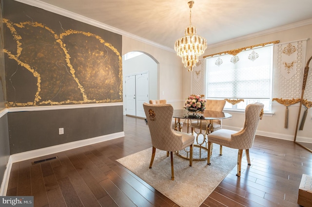 dining area featuring crown molding, dark wood-type flooring, and an inviting chandelier