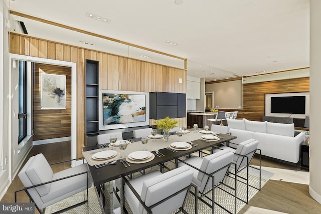 dining space with wooden walls and light hardwood / wood-style floors