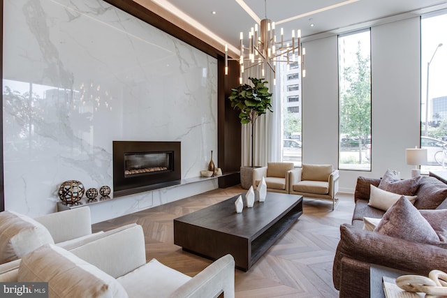 living room featuring an inviting chandelier, a fireplace, and light parquet flooring