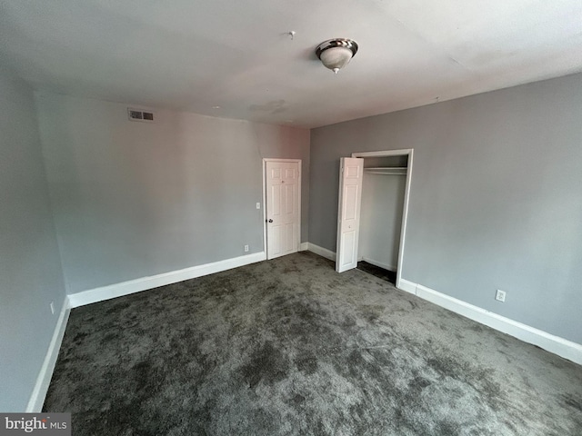 unfurnished bedroom with a closet and dark carpet