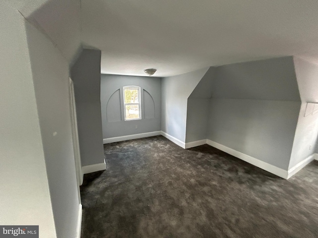 bonus room featuring vaulted ceiling and dark colored carpet