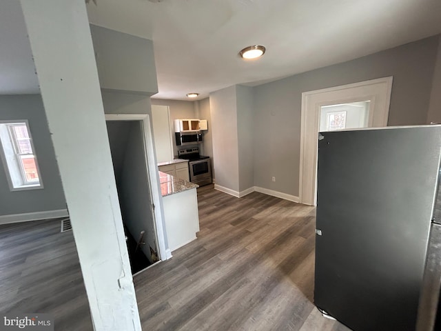 kitchen with white cabinets, light stone countertops, dark hardwood / wood-style floors, and appliances with stainless steel finishes