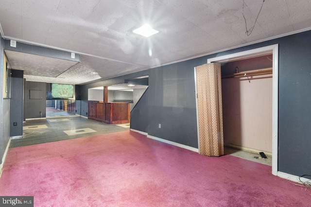 basement with carpet, crown molding, and a textured ceiling