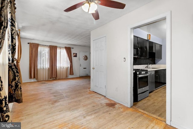 kitchen featuring sink, stainless steel gas range oven, light hardwood / wood-style flooring, and ceiling fan