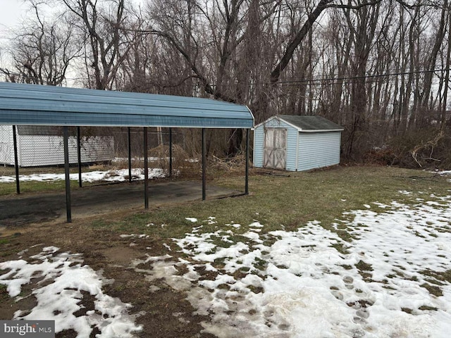 yard covered in snow featuring a carport and a storage shed