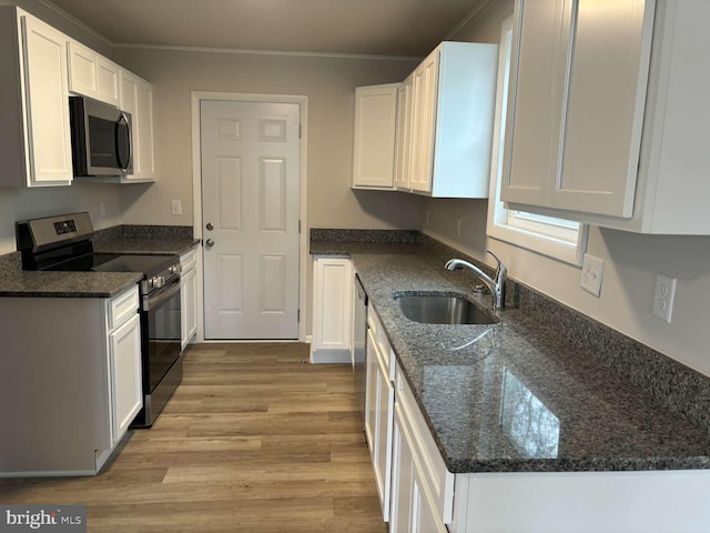 kitchen featuring white cabinets, stainless steel appliances, dark stone counters, and sink