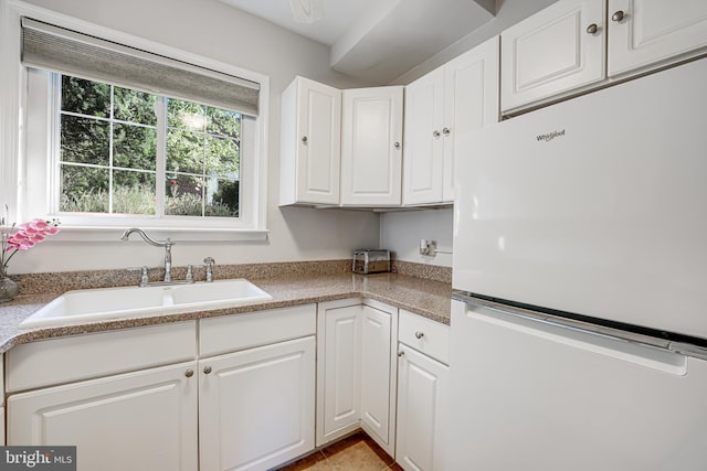 kitchen featuring sink, white cabinetry, and white fridge