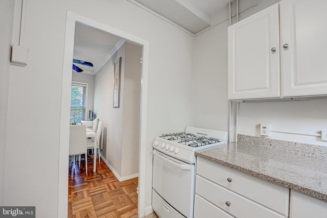 kitchen featuring white cabinetry, light stone counters, ornamental molding, parquet flooring, and white gas stove