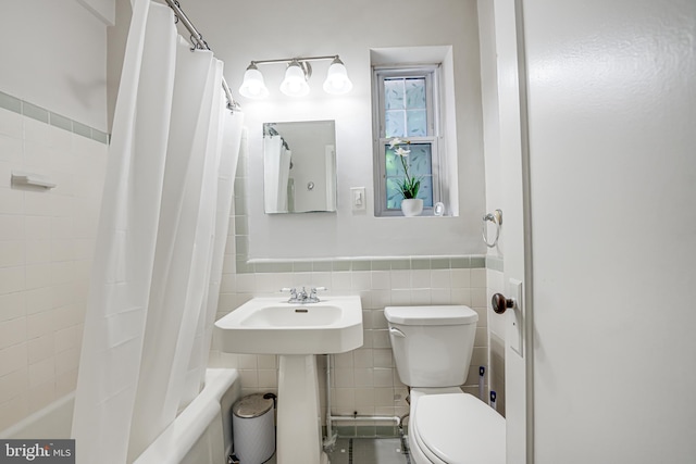 bathroom with toilet, tile walls, and shower / bath combo with shower curtain