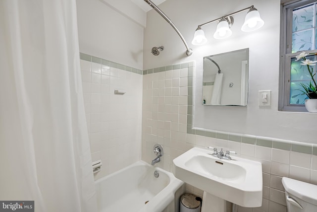 full bathroom with sink, toilet, shower / bathtub combination with curtain, and tile walls