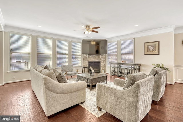 living room with crown molding, dark wood-type flooring, ceiling fan, and a fireplace