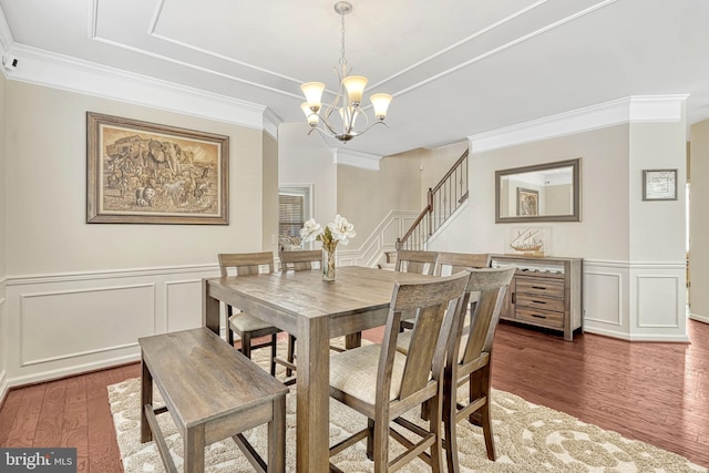 dining area featuring ornamental molding, dark wood-type flooring, and an inviting chandelier