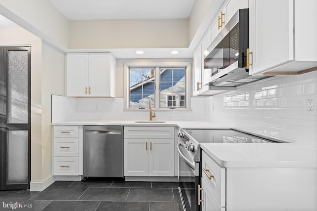 kitchen with dark tile patterned floors, decorative backsplash, white cabinets, sink, and stainless steel appliances