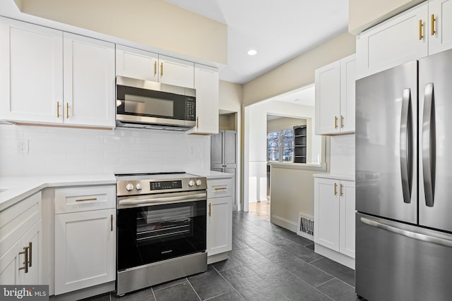 kitchen with white cabinets, appliances with stainless steel finishes, and tasteful backsplash