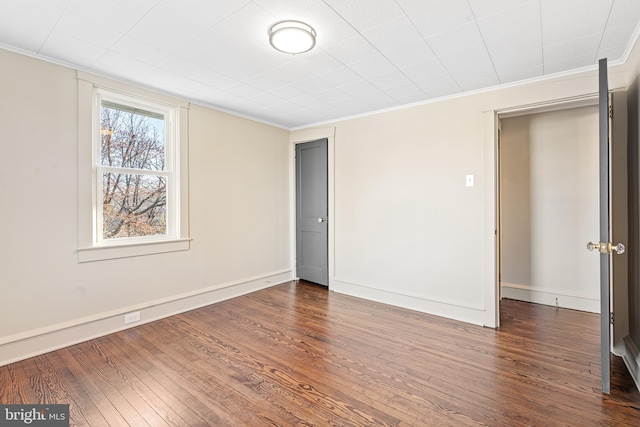 unfurnished bedroom featuring crown molding and dark wood-type flooring