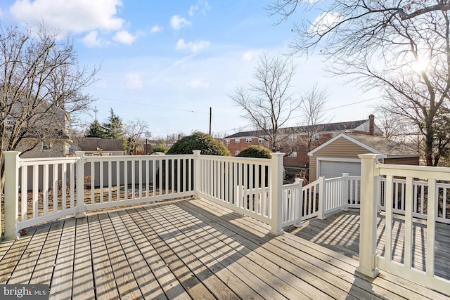 wooden deck featuring a garage and an outbuilding