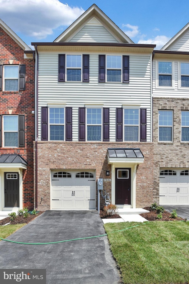 view of property featuring a garage and a front lawn