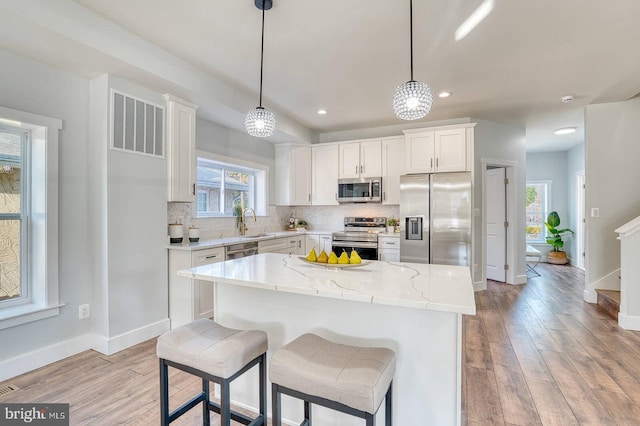 kitchen with pendant lighting, a center island, white cabinets, and appliances with stainless steel finishes