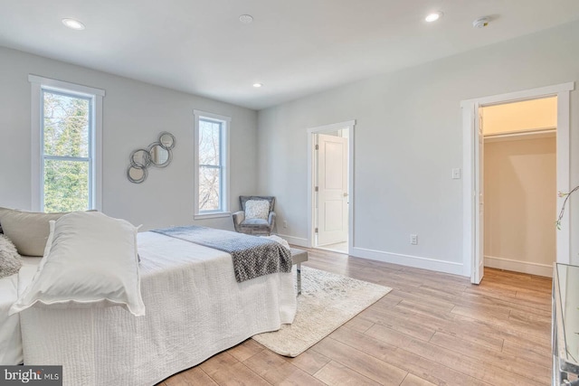 bedroom with a walk in closet, a closet, and light wood-type flooring