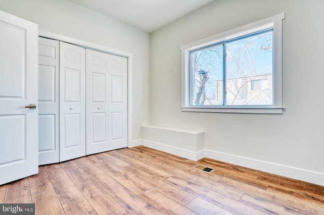 unfurnished bedroom featuring light wood-type flooring and a closet