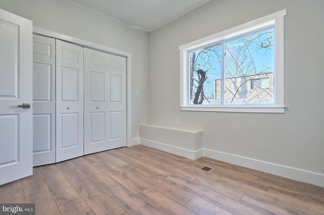 unfurnished bedroom with wood-type flooring and a closet