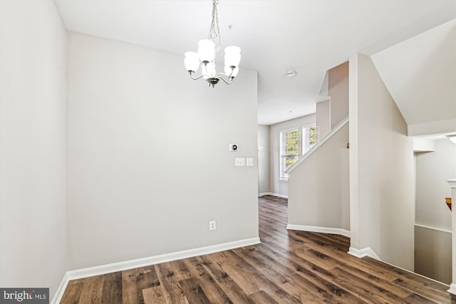 unfurnished room with dark wood-type flooring and a notable chandelier