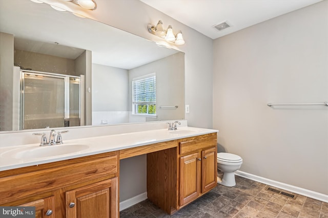 bathroom with vanity, toilet, and a shower with door