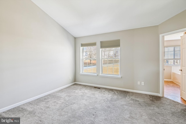 spare room featuring light carpet and lofted ceiling