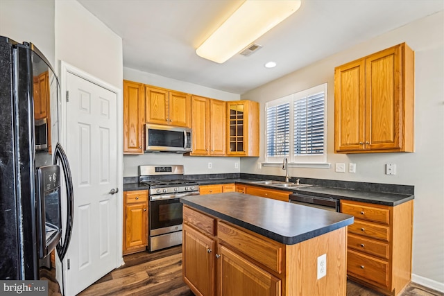 kitchen with appliances with stainless steel finishes, a center island, sink, and dark wood-type flooring