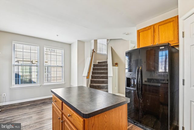 kitchen with dark hardwood / wood-style floors, black refrigerator with ice dispenser, and a center island