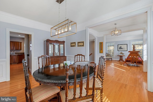 dining area with sink, light hardwood / wood-style flooring, and ornamental molding