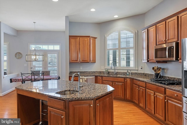 kitchen with sink, hanging light fixtures, an island with sink, and black gas cooktop