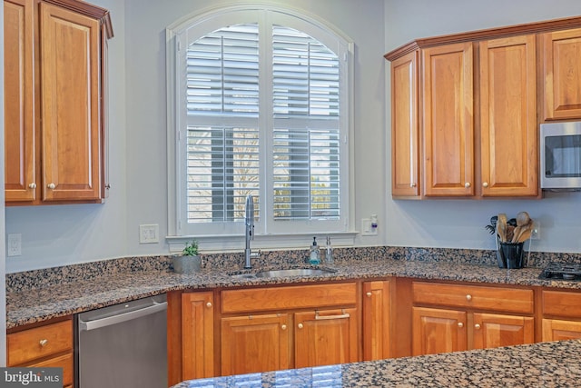 kitchen featuring stainless steel appliances, sink, and dark stone countertops